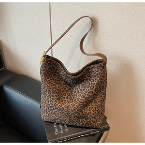Detail of vintage leopard print hobo bag with leather strap and golden buckle on a sofa