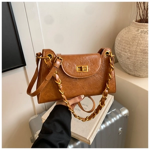 Close-up of brown pleated leather texture with gold square metal lock and chain handle