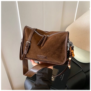 Detail der braunen Wildledertasche mit Doppelreißverschluss und Holzperlen-Anhänger