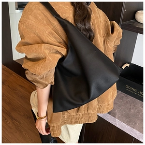 Gros plan d'un grand sac hobo noir mat avec des plis en cuir souple porté par un mannequin