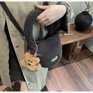 Détail du sac seau en peluche marron avec breloque ours et étiquette tissée texte
