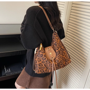 Detail of leopard print tote bag featuring a leather buckle with golden flower emblem