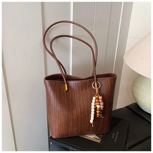 Dettaglio della borsa tote marrone intrecciata vintage con ciondolo in perle di legno