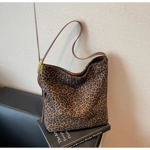 Close-up of leopard print tote bag with brown leather strap and golden metal buckle details