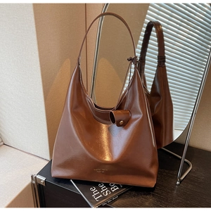 Détail du sac Hobo marron avec surpiqûres contrastées et nœud sur la bandoulière