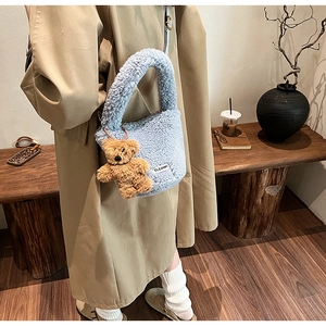 Détail du sac à main en peluche bleu clair avec breloque ours en peluche sur bois