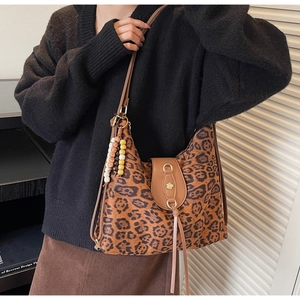 Detail of leopard print tote bag with metallic flower buckle and beaded tassel accents