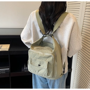 Detailed view of the light green nylon backpack showing waterproof texture and zipper pockets