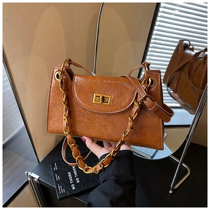 Close-up of brown pleated leather handbag featuring a vintage gold chain and clasp lock