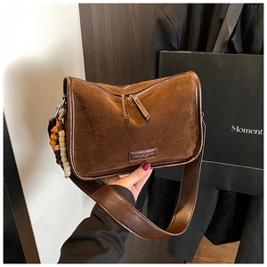 Detaillierte Nahaufnahme der braunen Wildledertasche mit bunten Holzperlen und Logo-Patch