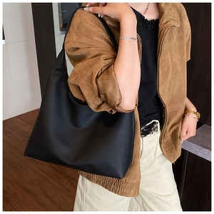 Grand sac hobo en cuir noir porté par un mannequin dans une tenue d'automne décontractée