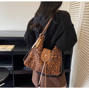 Detail of leopard print tote bag with brown leather strap and wooden bead tassel decoration