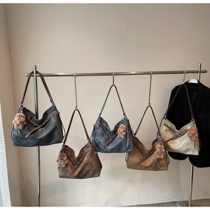 Detail view of five colors of vintage washed leather tote bags with cute bear charms