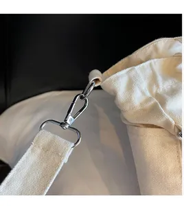 Close-up of durable silver lobster clasp and reinforced canvas strap on beige tote bag