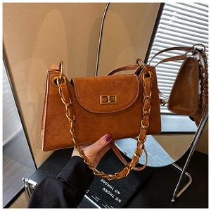 Detail of caramel brown pleated shoulder bag with vintage gold chain and turn-lock closure