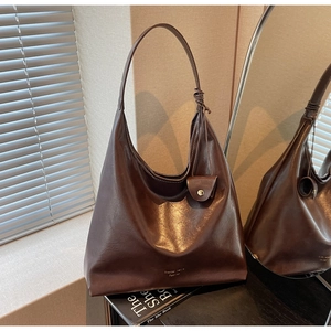 Détail du sac cabas en cuir marron foncé avec petite pochette assortie et logo gravé