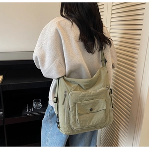 Detail of sage green nylon tote bag with functional pockets and wide strap on model