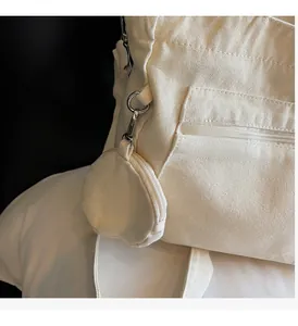 Close-up of off-white canvas tote bag featuring a detachable round coin purse on the side