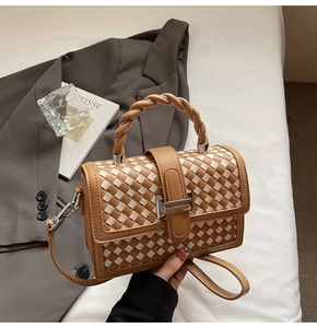 Detail of a brown and white woven square bag with silver clasp and twisted handle