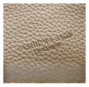 Detailed close-up of premium lychee grain leather with debossed fashion text on tote bag