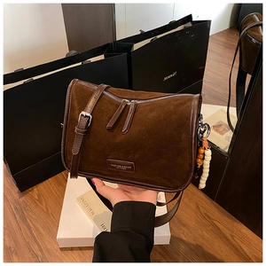 Detail der braunen Wildledertasche mit Holzperlenquaste und silbernem Metallreißverschluss