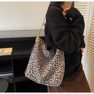 Detail of leopard print tote bag featuring brown leather strap and gold buckle accent