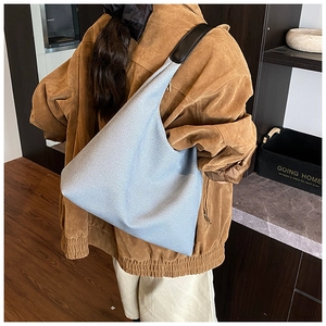 Gros plan sur un sac hobo en tricot bleu clair avec bandoulière en cuir noir sur un mannequin