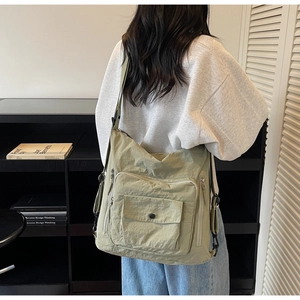 Detail of light green nylon tote bag with adjustable strap and side zipper pockets