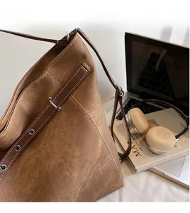 Close-up of vintage brown canvas tote bag with adjustable leather straps and white stitching