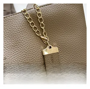 Detail of leather tote bag charm with golden metal chain and embossed FASHION lettering