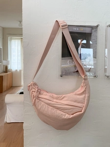Chic pink nylon crescent hobo bag with adjustable wide shoulder strap in home setting