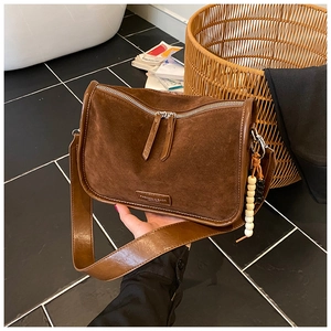 Detailansicht braune Wildledertasche mit Lederriemen und Anhänger aus Holzperlen