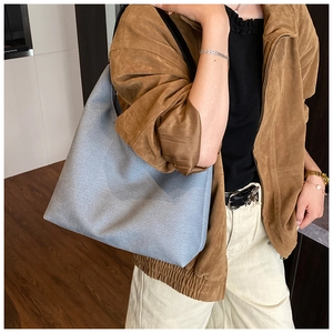 Grand sac fourre-tout gris-bleu avec lanières noires porté par un mannequin en intérieur