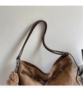 Detailed shot of brown tote bag featuring durable leather handles and cute bear charm