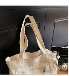 Detail of canvas tote bag showing front zipper pocket and reinforced wide handles