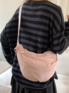 Pink crescent-shaped nylon crossbody bag with adjustable wide shoulder strap for women