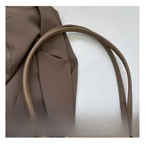 Detail of lychee pattern leather tote bag handle with gold hardware and neat stitching