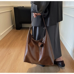 Détail du sac cabas marron vintage avec pendentif rond et vue latérale sur mannequin