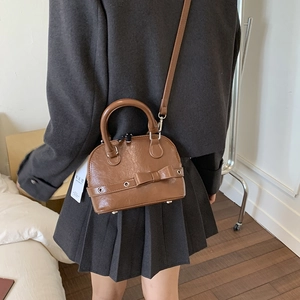 Rear view of brown shell-shaped crossbody bag on a grey blazer outfit for styling