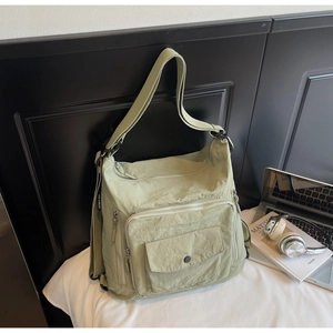 Detail of sage green nylon crossbody bag with multi-pocket design and adjustable strap
