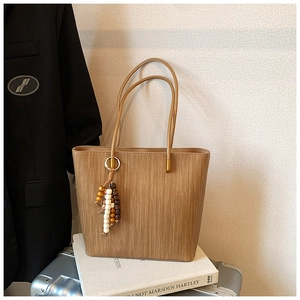 Dettaglio della borsa tote intrecciata marrone caffè con perline e nappa colorata
