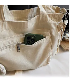 Close-up of beige canvas tote bag featuring a front zipper pocket for smartphone storage