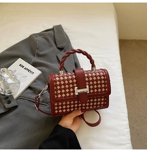 Detail of maroon and beige woven square handbag with twisted handle and silver buckle