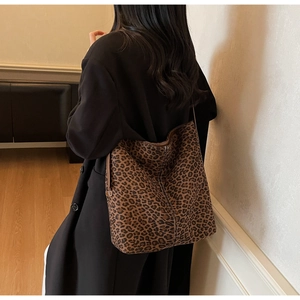 Detail of leopard print tote bag with brown leather trim and white stitching details