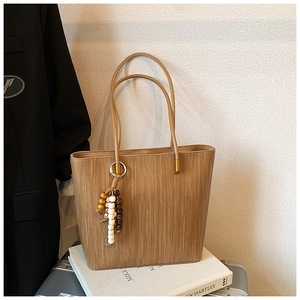 Dettaglio della borsa tote kaki con trama verticale e nappa decorativa in legno