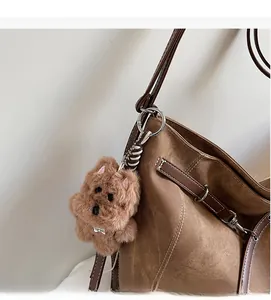 Detail of brown plush puppy bag charm with TOP DOG tag on a large tote bag
