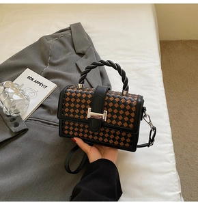 Detail of woven checkerboard texture and twist handle on the crossbody square bag