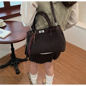 Close-up of retro brown handbag featuring matte and patent leather with silver turn-lock