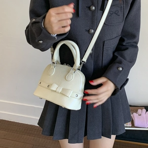 Detail of cream white shell-shaped handbag featuring a 3D bow and silver hardware