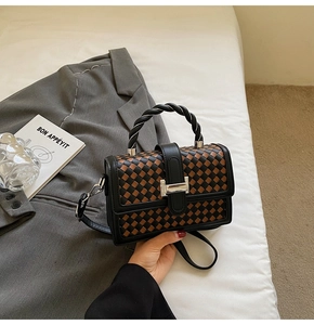 Detail of square woven handbag with leather texture and silver buckle on white bedding